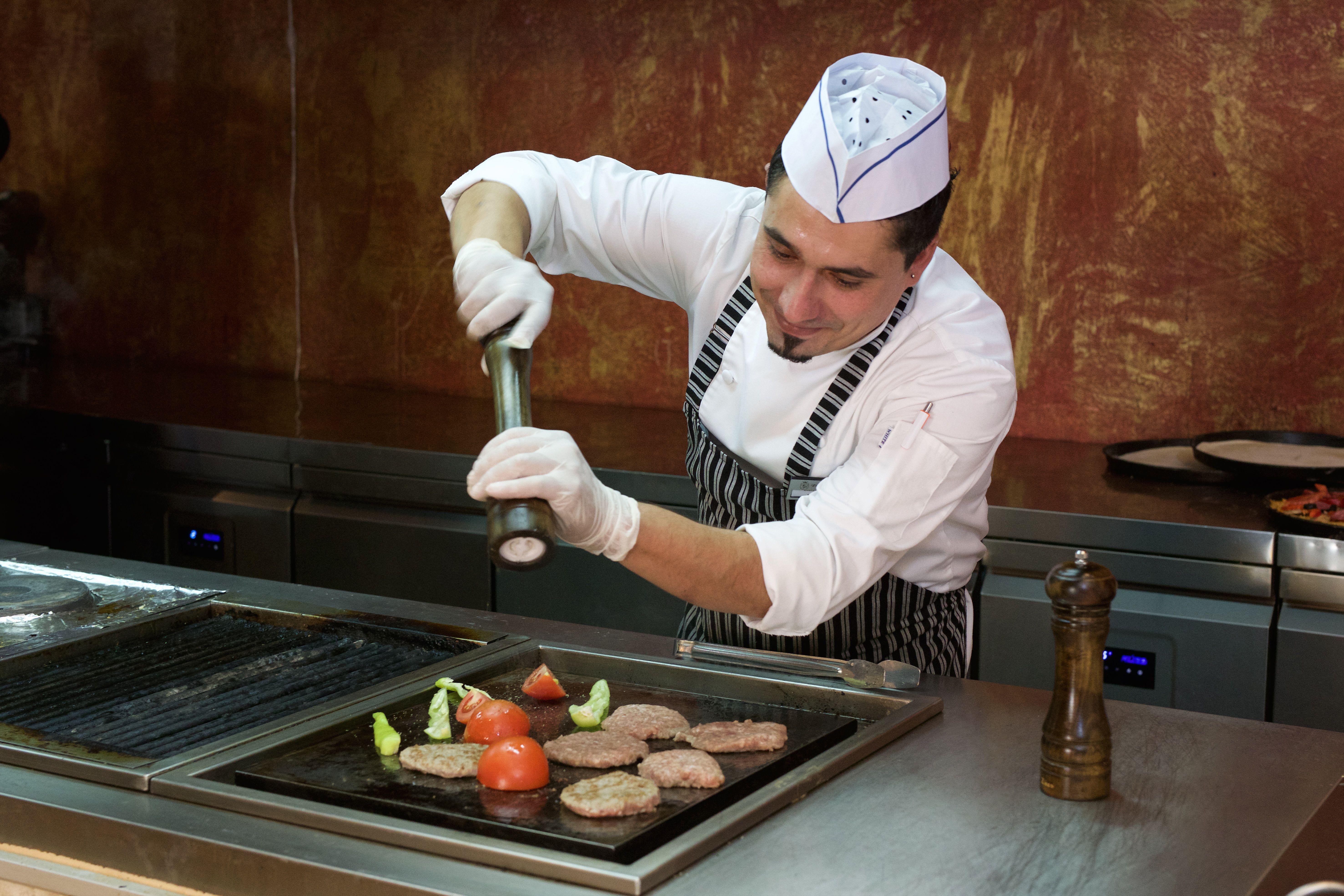 Imperial Palace Hotel Pantai Sunny Luaran gambar A sous-chef seasoning food